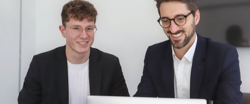 Personen sitzen vor einem Laptop.